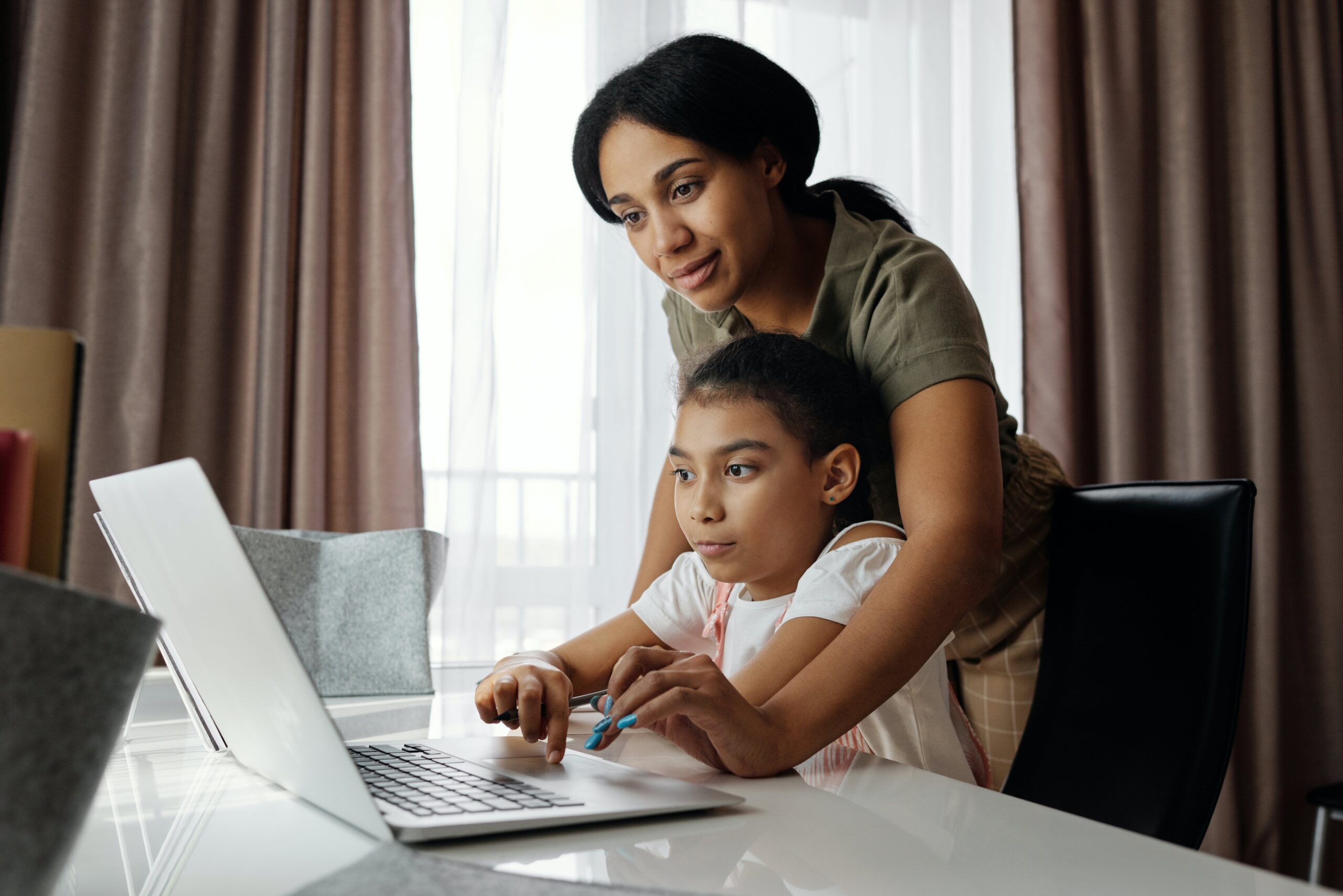 Woman using a laptop while holding her child