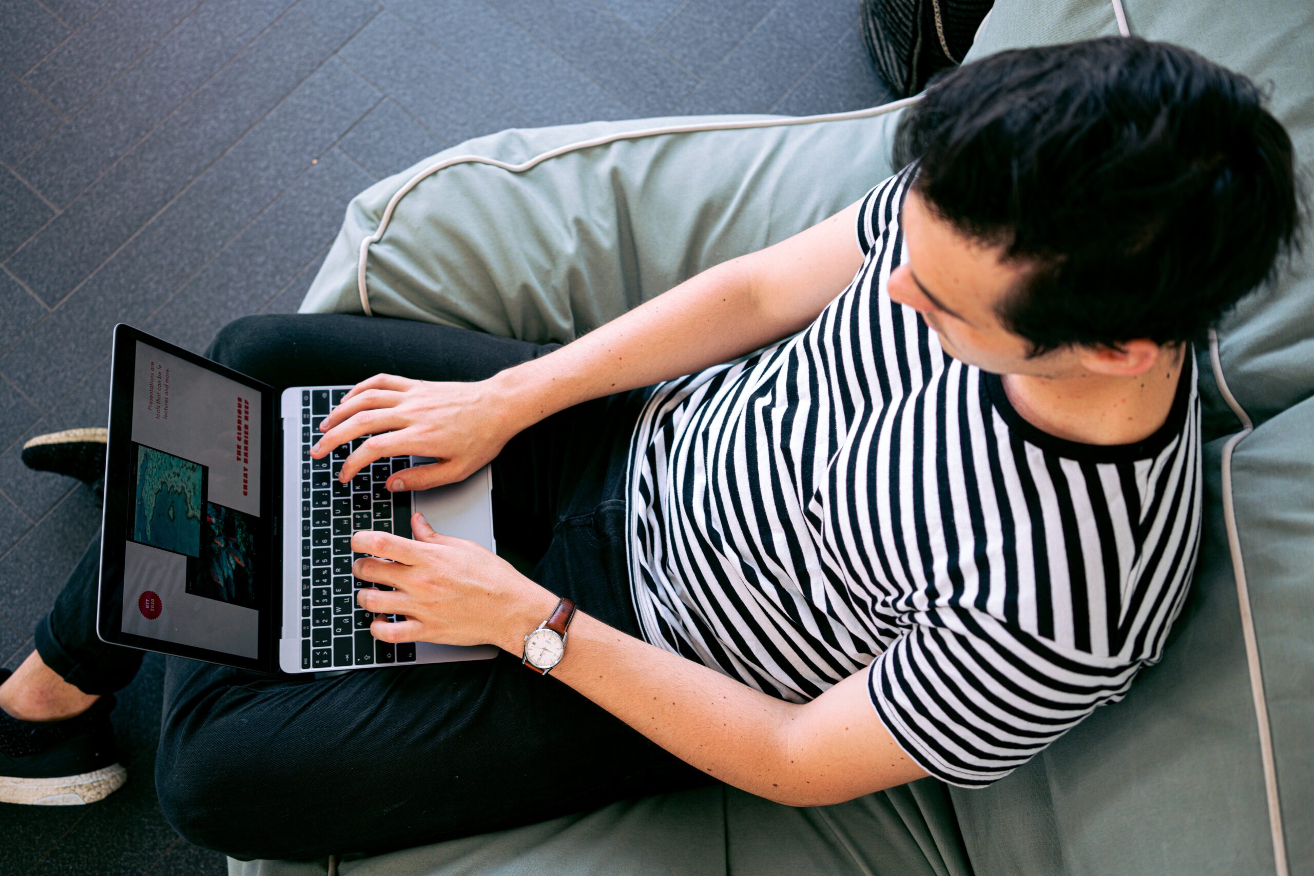 Man in a striped shirt sitting on a couch and using a laptop
